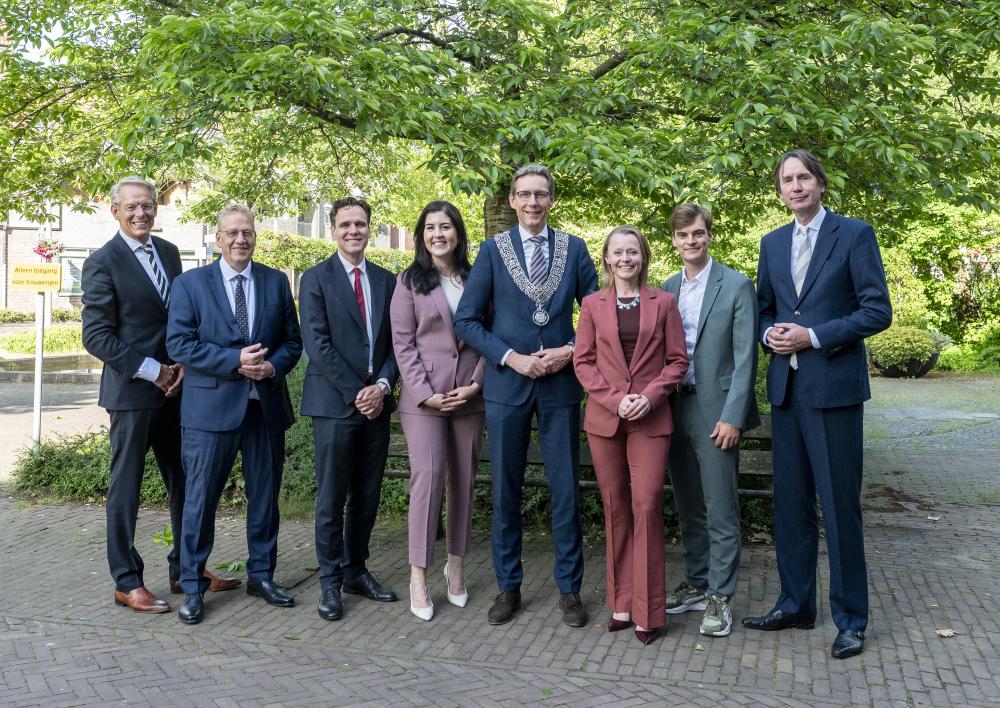 Groepsfoto van de wethouders voor een boom bij het raadhuis