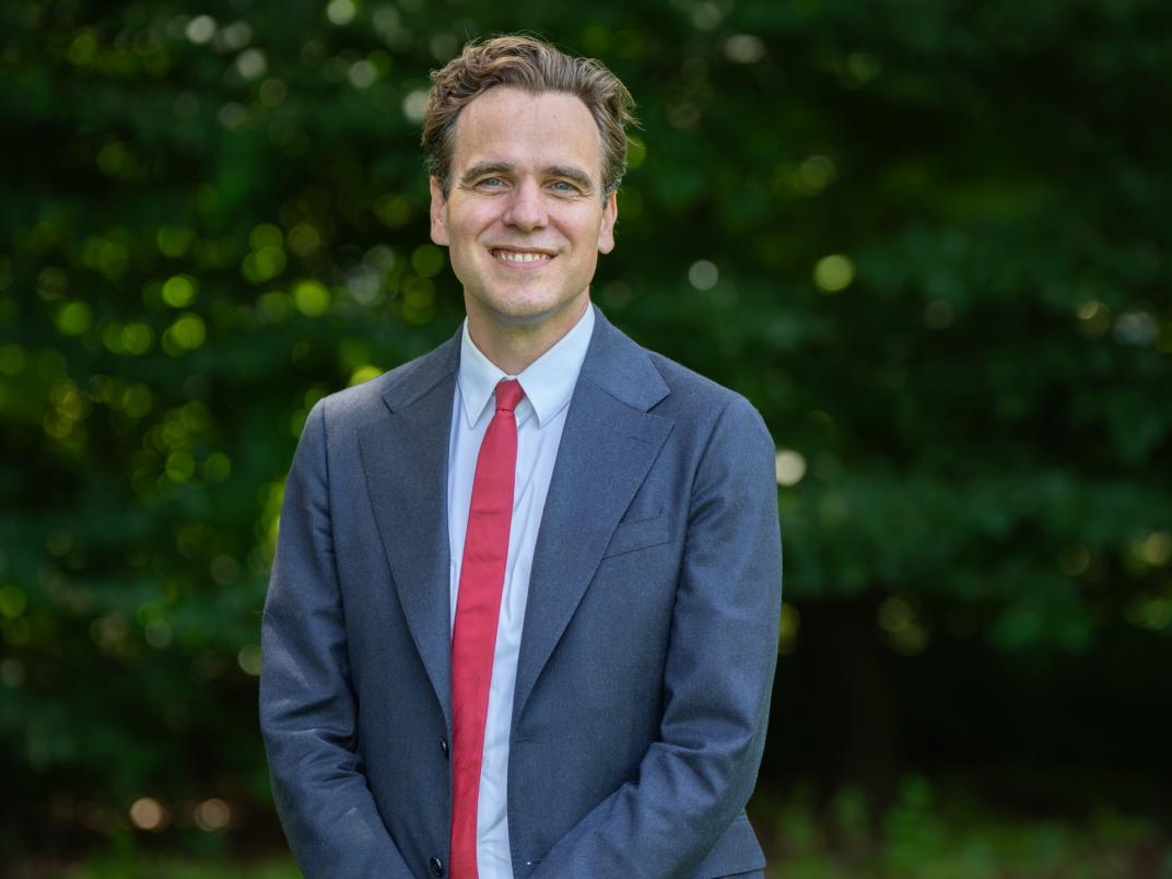Portretfoto wethouder Marijn van Ballegooijen met groene achtergrond